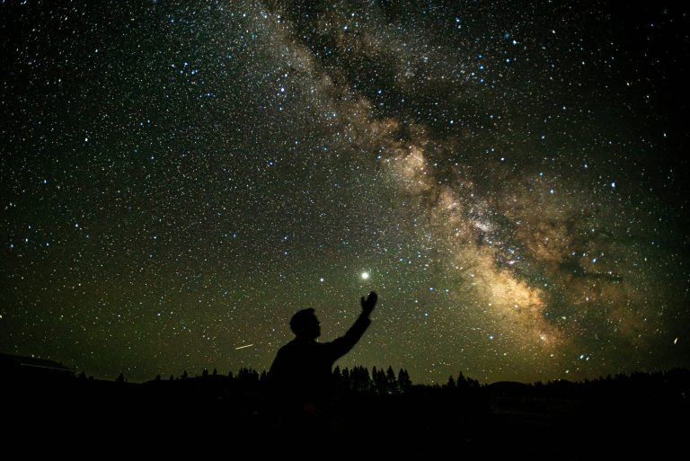 Shadow of a person looking up at a night sky and Milky Way. Image used to depict nighttime and dreams